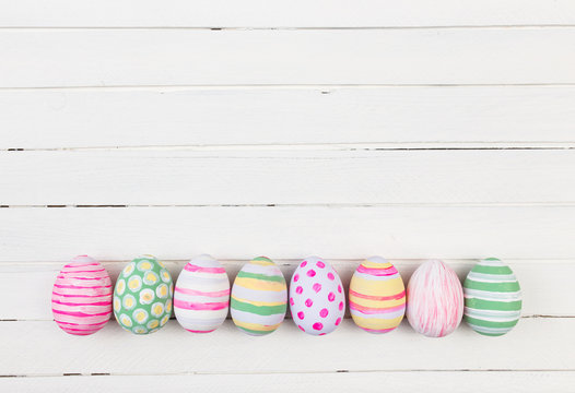 Easter eggs painted in pastel colors on a white wood background