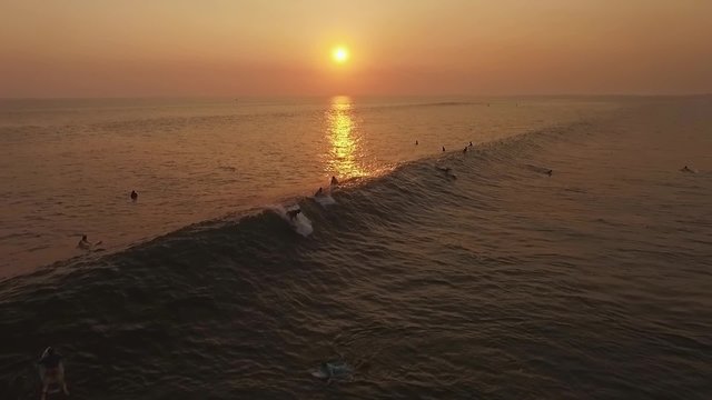 Surfer riding a wave during a beautiful sunset. This is a slow motion shot.
