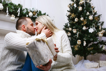 Young beautiful couple kissing on the background of Christmas tr