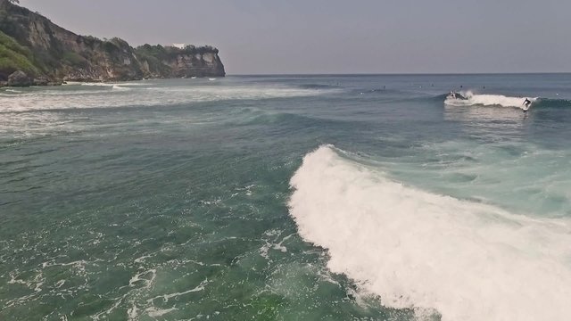 Aerial footage of a surfer in the Uluwatu water. Slow motion shot.