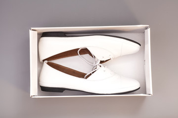 Pair of womans white shoes in box isolated on gray background