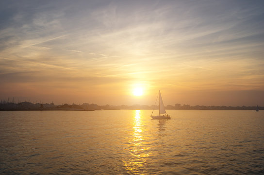 a boat sailing on the sea with the sunset as background - nature, transportation and lifestyle concept