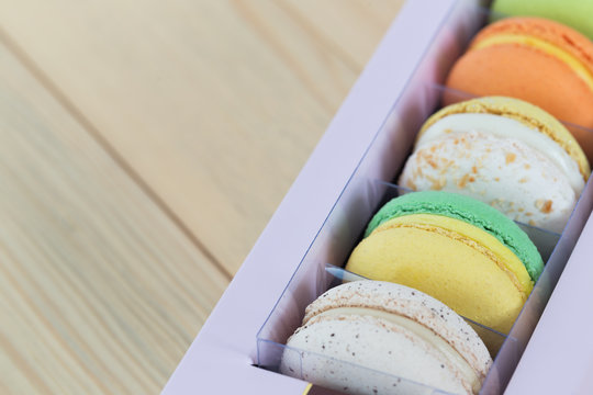 Colorful Macaroons boxset on wooden background.