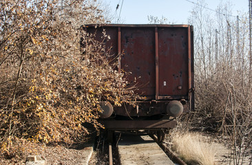Old vintage rusty metal freight railway wagon in neglected sidetrack