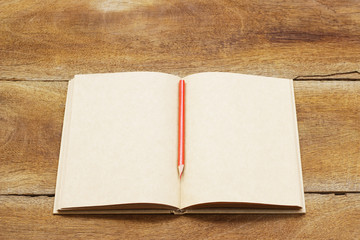 Notebook and pencil with plumaria flower on wooden table