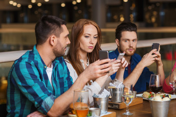 friends with smartphones dining at restaurant