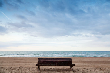 Fototapeta na wymiar Old empty bench stands on sandy beach