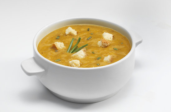 Овощной суп-пюре с гренками в фарфоровой тарелке на белом фоне