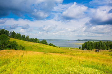 The lake , forest, field , big clouds