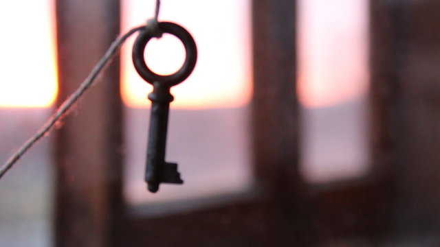 Old key, hanging on a string. Sunset on background.