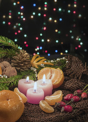 Fototapeta na wymiar Christmas Christmas candles and ornaments, tangerines and nuts on a dark background with lightscandles and ornaments over dark background with lights