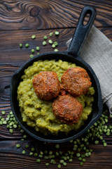 Frying pan with meatballs and green peas, top view, close-up