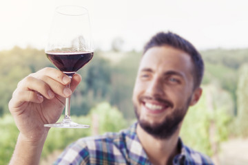 handsome bearded man looking glass of wine before drinking