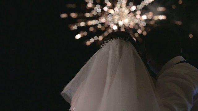the bride and groom looking at fireworks