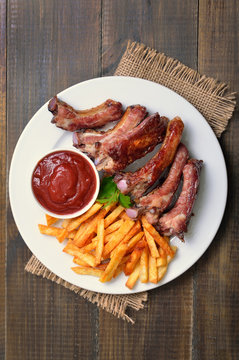 Fried pork ribs, potato fries and tomato sauce, top view