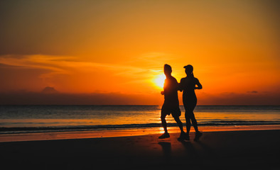 Fototapeta premium Young couple: man and woman run together on a sunset on lake coa