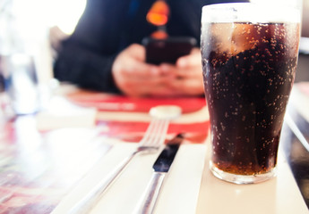 glass of cola with ice in cafe