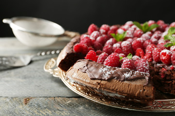 Cake with Chocolate Glaze and raspberries on tray on dark background