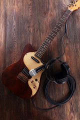 Fototapeta premium Electric guitar, microphone, and headphones on wooden background for music production and recording studio setup