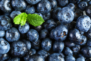 Tasty ripe blueberries with green leaves close up