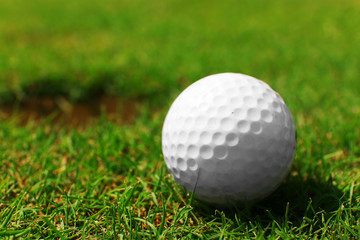 Golf ball on lip of cup on the green golf course, close up