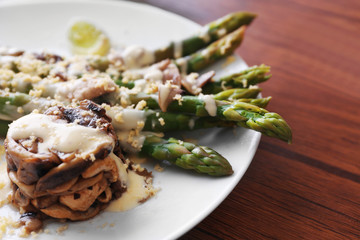 Delicious dish with asparagus and mushrooms on served wooden table in the restaurant, close up