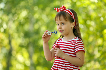 Little girl playing with bubbles in the park