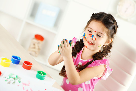 Cute little girl painting picture on home interior background