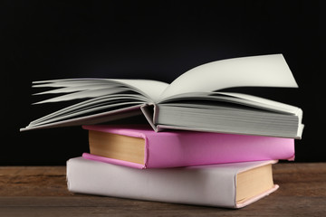 Pile of books on wooden table against black background