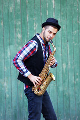 The musician plays saxophone on green wooden background