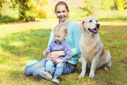 Happy Mother And Child With Golden Retriever Dog On Grass In Par