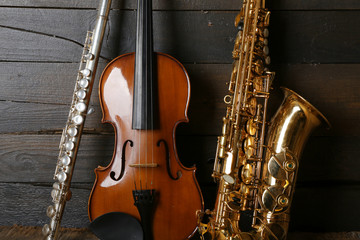 Obraz premium Musical instruments: saxophone, violin and flute on wooden background