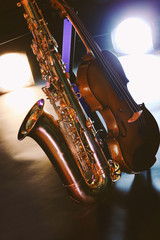 Obraz premium Beautiful golden saxophone with violin on a scene