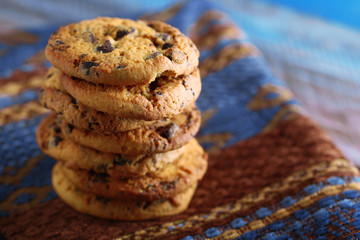 Cookies with chocolate crumbs on ornament napkin against blurred background, close up