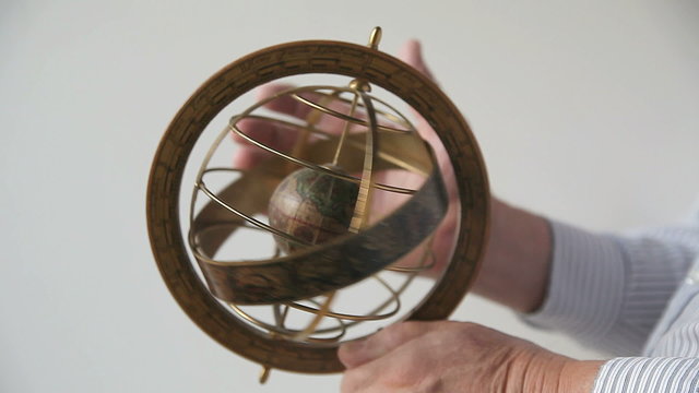 A man holds and spins a model of an armillary sphere.