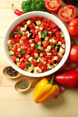 Ratatouille before cooking and ingredients, on wooden background