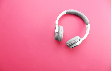 Wireless white and grey headphones on pink background