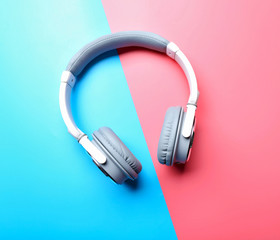 Wireless white and grey headphones on pink-blue background