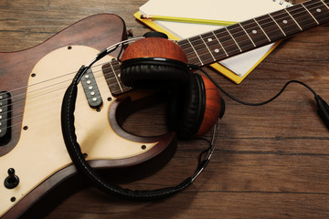 Electric guitar and headphones on wooden background