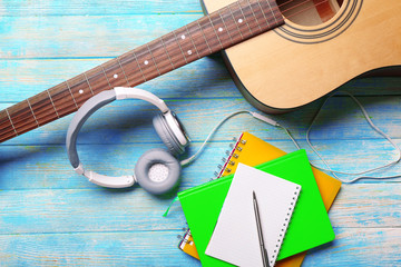 Headphones with guitar and notebook on blue wooden background