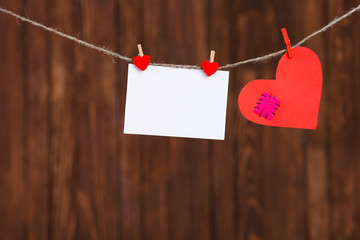Red heart and blank note, on wooden background