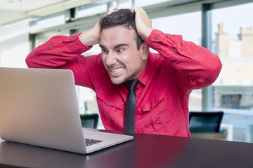 Man frustrated at lap top in office