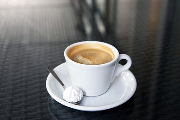 Cup of tasty coffee, zephyr and spoon in cafe