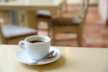 Cup of tasty coffee with spoon in cafe