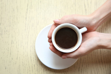 Cup of coffee with hands on table background