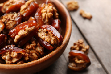 Walnut and date fruit in bowl on wooden table, close-up