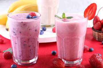 Milkshakes with berries at red textile on light background