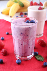 Milkshakes with berries at red textile on light background, close-up