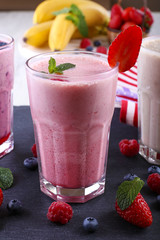 Milkshakes at cutting board with berries on light background, close-up