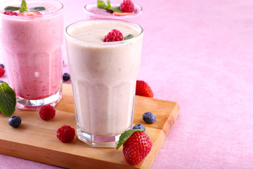 Milkshakes at cutting board with berries on light background